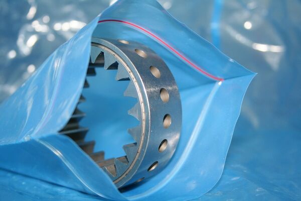 VCI-Folie für Korrosionsschutz von Metallteilen und Präzisionskomponenten Metallisches Zahnrad bzw. Präzisionsbauteil in blauer VCI-Folie verpackt. Die VCI-Korrosionsschutzfolie schützt Metallteile zuverlässig vor Rost und Korrosion während Lagerung, Transport und Exportverpackung.