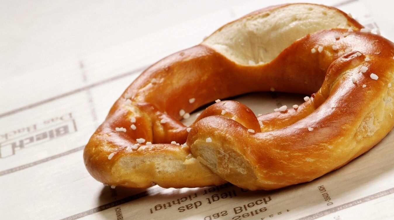 Frisch gebackene Brezel auf Blechrein Backtrennpapier mit leicht glänzender, goldbrauner Oberfläche.
