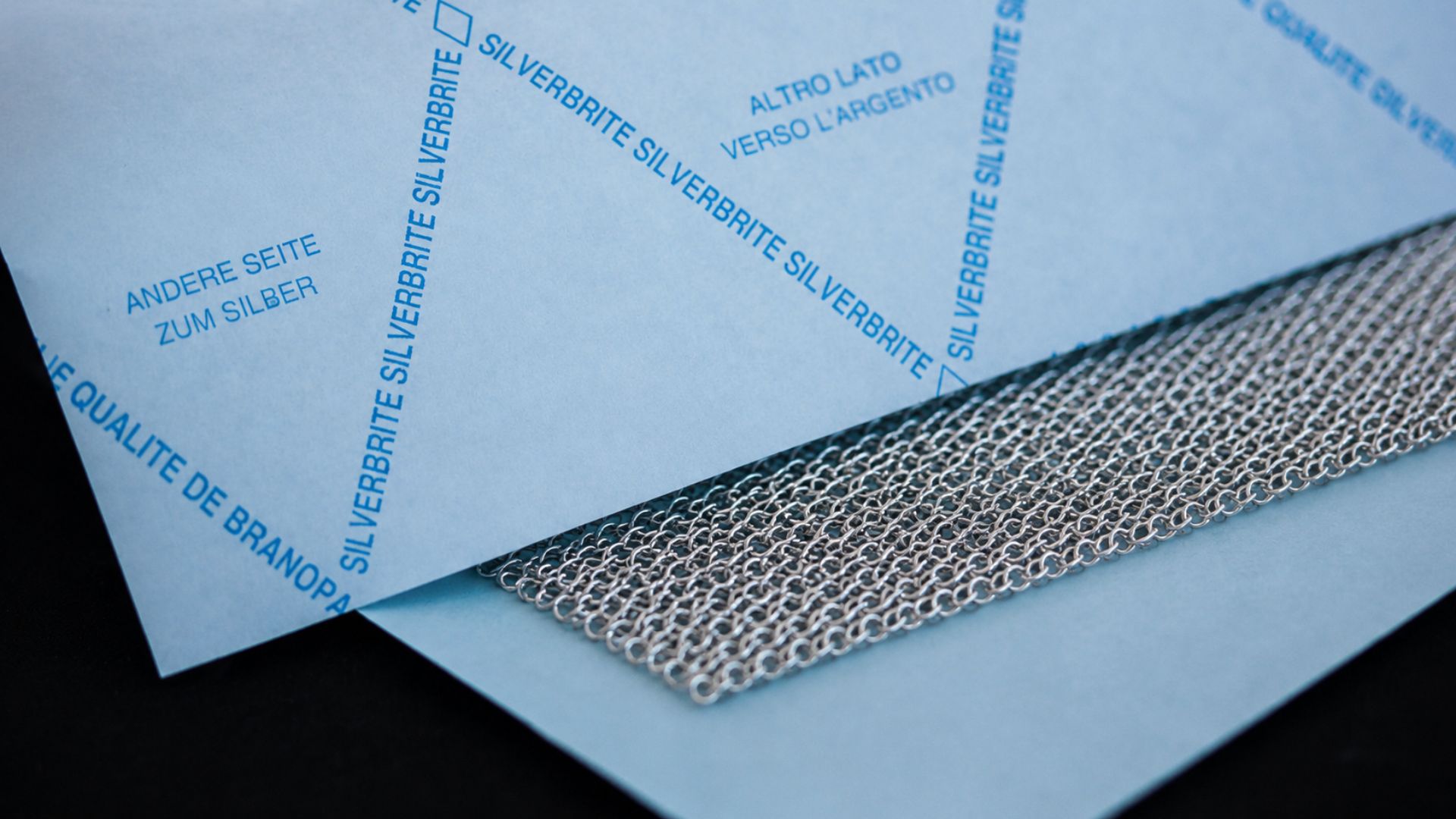 Makroaufnahme von SILVERBRITE Silberanlaufpapier mit hochwertigem Silbernetz in Nahaufnahme – technisches Schutzpapier für Silberwaren, Schmuck und empfindliche Metalloberflächen mit originalem blauem Druckbild und edler Produktinszenierung.
